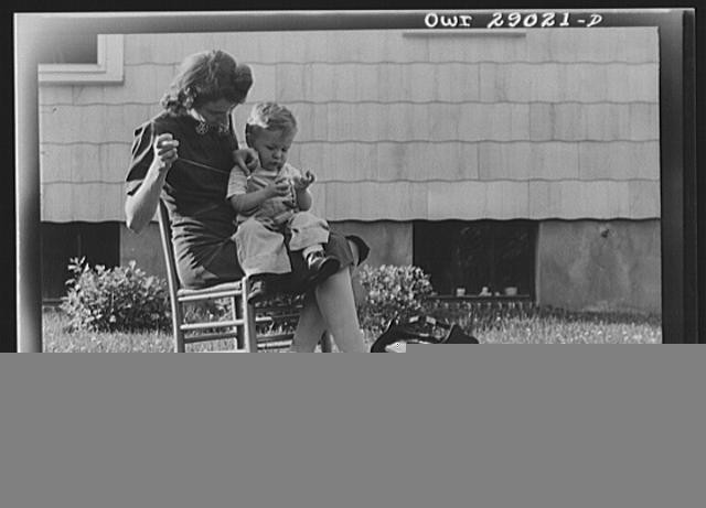 Maryland, A mother sewing a button on her child's overalls. Silver Spring