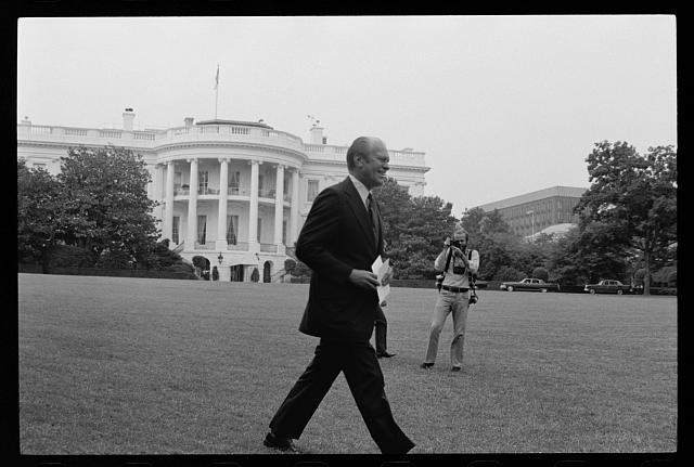 President Gerald Ford walking across the lawn to a press conference at the