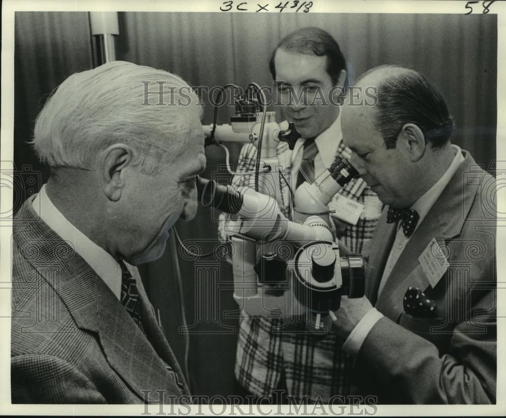 1975 Press Photo New Orleans Academy of Opthalmology Members Inspect Microscope-image