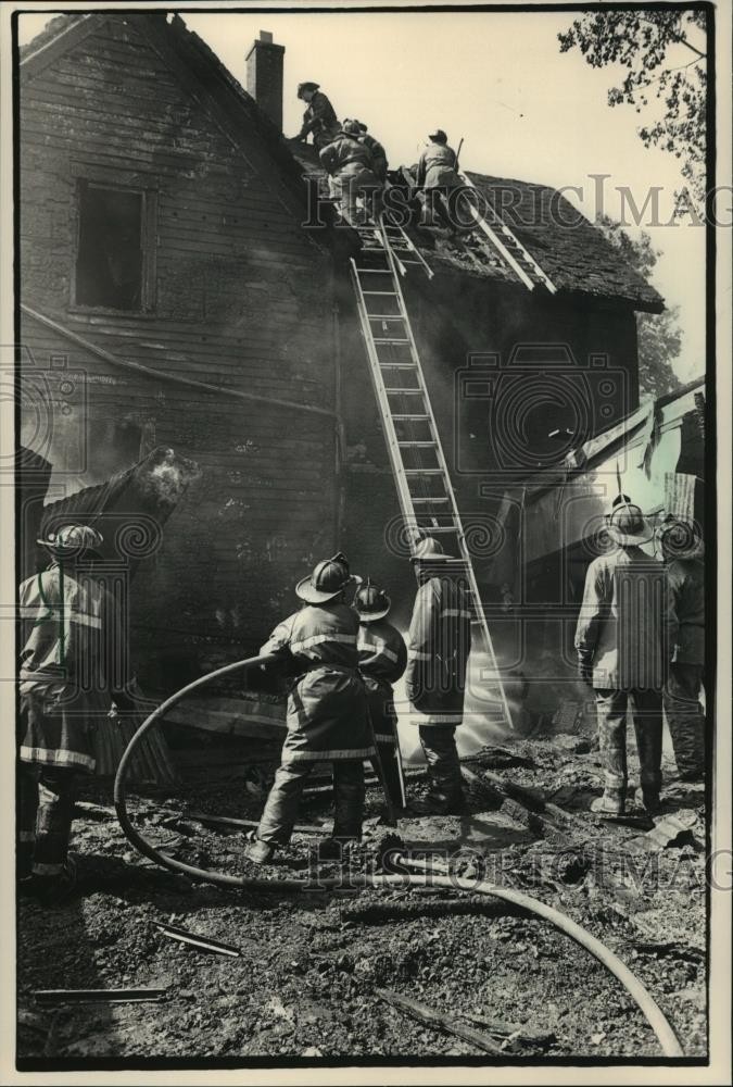 1987 Press Photo Firefighters fight fire on Roof of Burning Home in Milwaukee