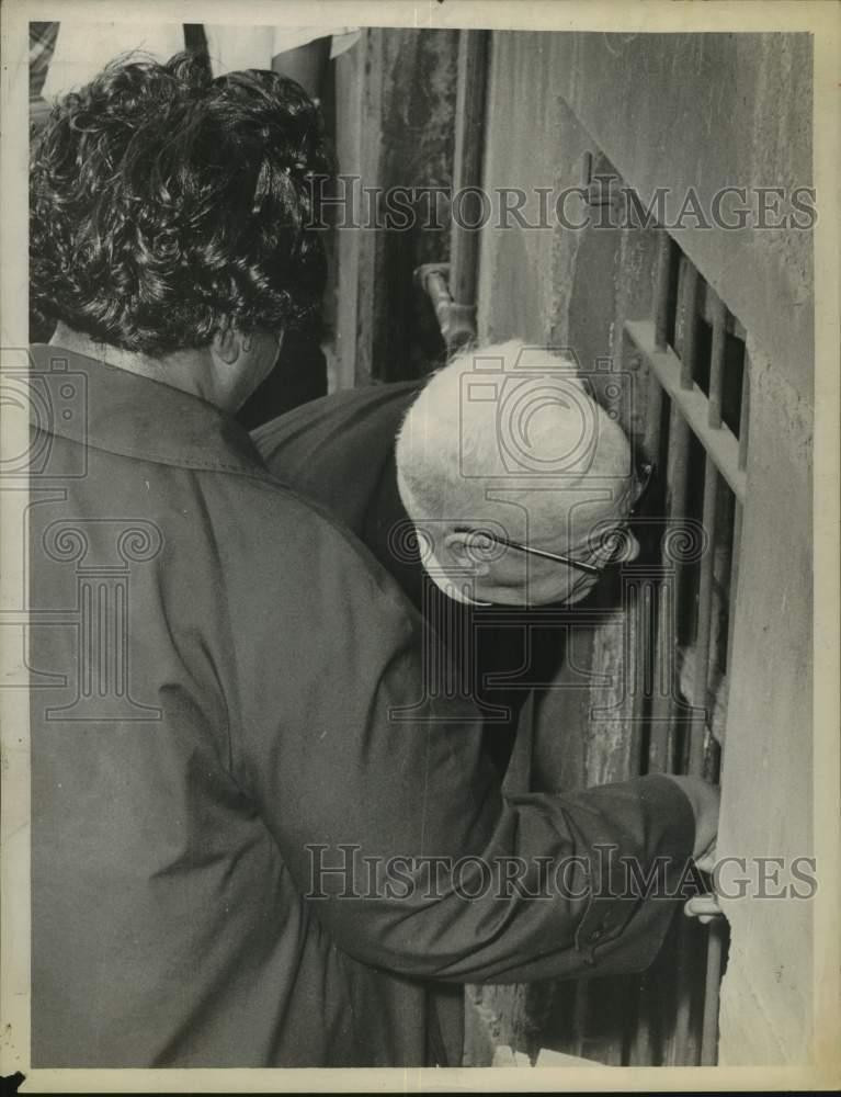 Press Photo Bishop Edward J Maginn looks into basement window covered with bars