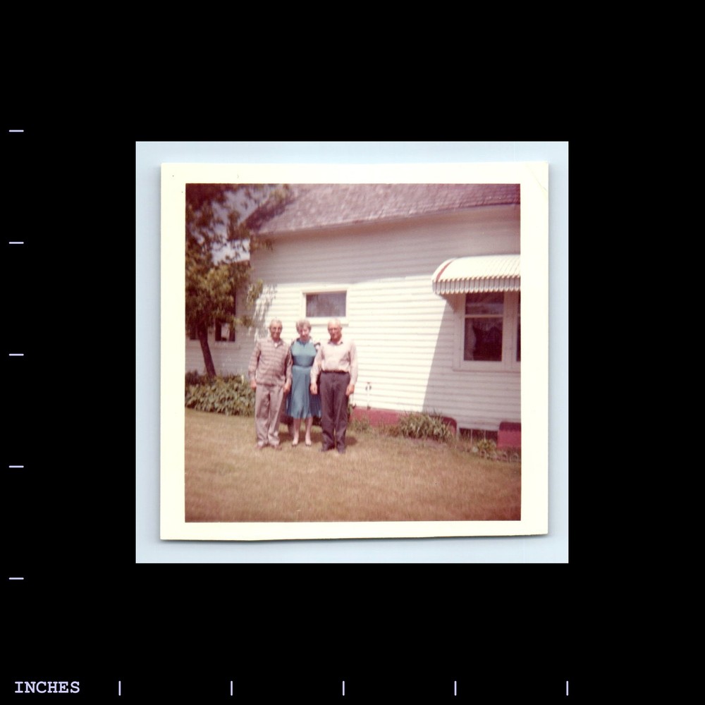 Square Color Photo MEN AND WOMAN STANDING OUTSIDE HOUSE