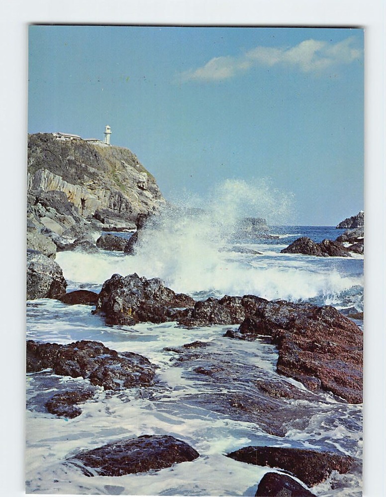 Postcard Waves Crashing Against Rocky Shore with Lighthouse on Cliff