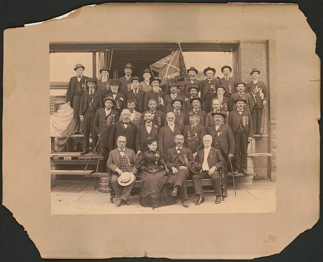 Civil War veterans of the 1st New York Dragoons wearing ribbons and with flag /