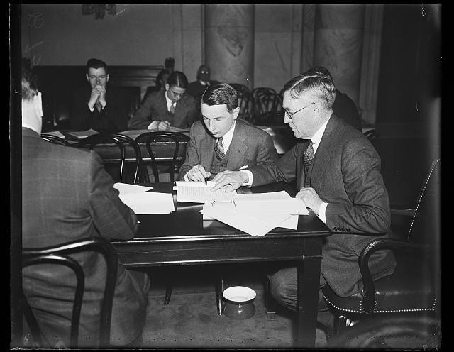 Photo:1935 Men Reading Documents at Table Meeting Conference Room