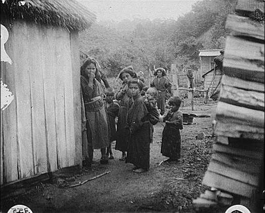 Group,Ainu children,passageway between huts,villages,structures,A Genthe,1908