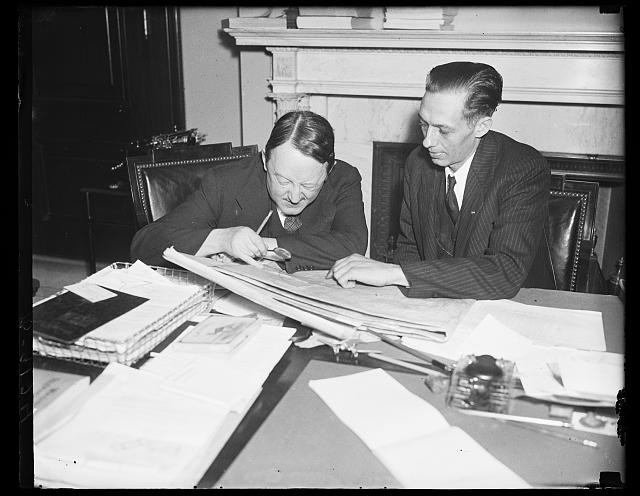 Photo:Two Men Reviewing Papers 1930s Office Desk Fireplace