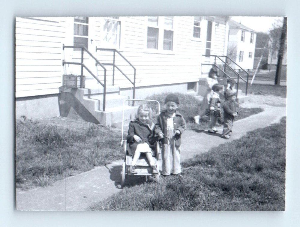 Old Vintage Photo BOYS GIRLS SITTING IN STROLLER OUTSIDE BUILDING 1950S