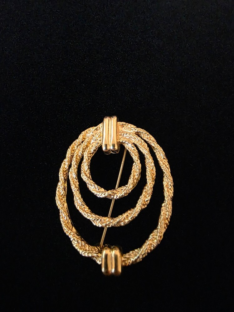 A vintage gold‑tone circular brooch featuring a triple‑rope textured design.