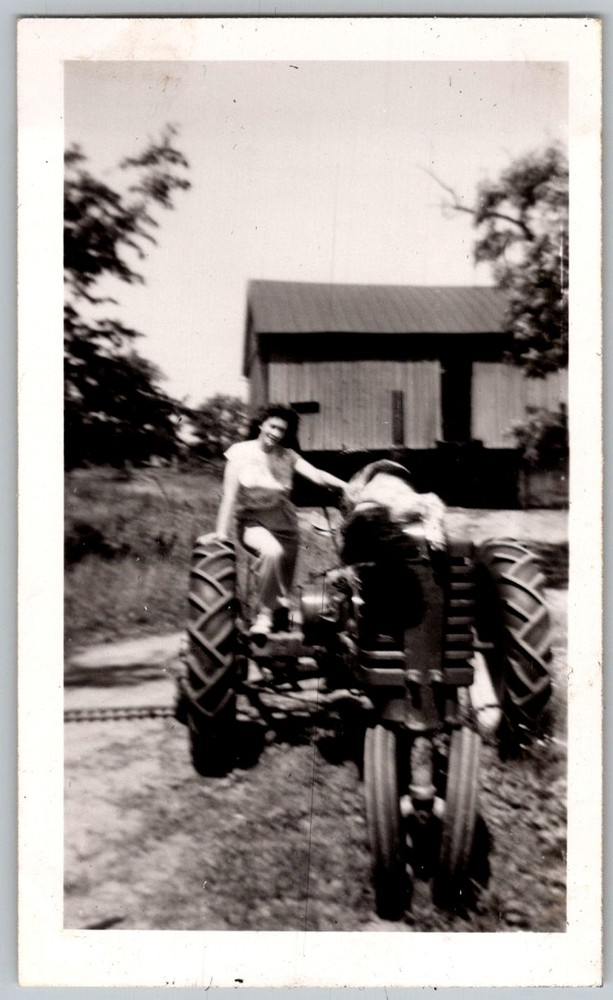 Vtg B&W Snapshot Woman in Overalls Sitting On Farm Tractor By Barn 1940s