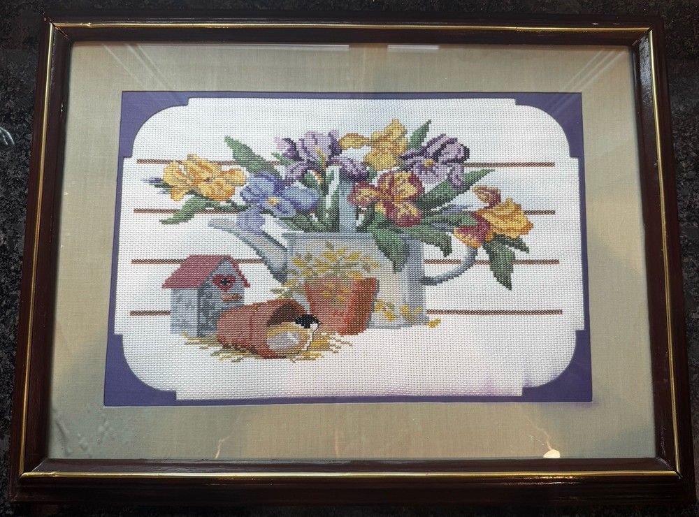 Vintage cross-stitch needlepoint framed watering can with flower bouquet.