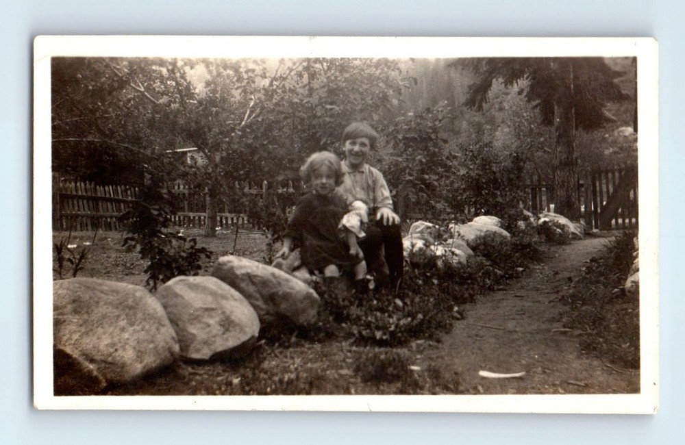 Old Vintage Photo BOY AND GIRL WITH DOLL SITTING ON ROCKS IN YARD SNAPSHOT