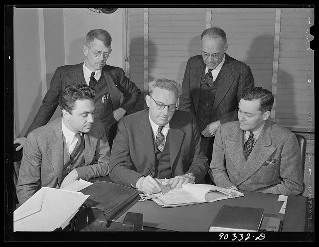 Photo:Men at Desk Signing Documents 1930s Office Meeting