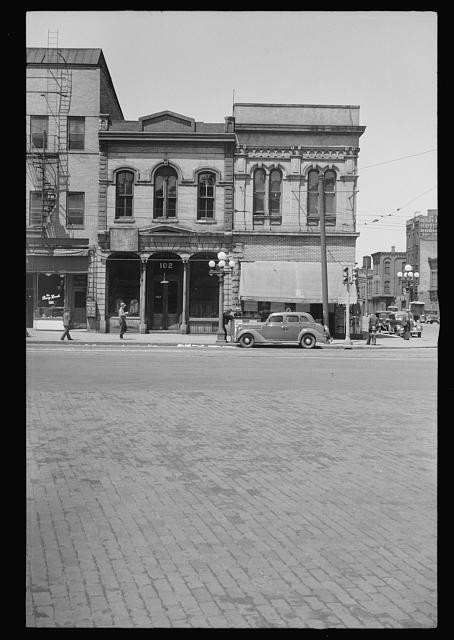 Photo:1930s Downtown Street Storefronts Automobile Brick Buildings