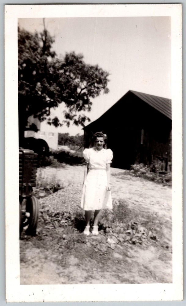 Vtg B&W Snapshot Young Woman in White Dress On Farm With Tractor & Barn 1940s