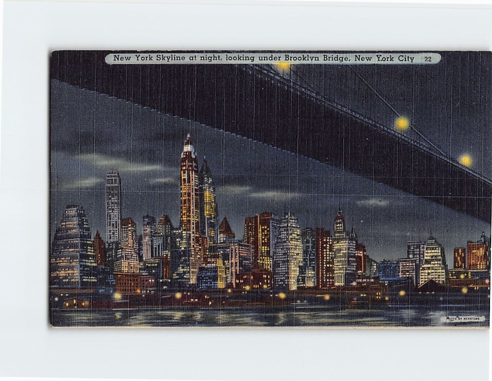 Postcard New York Skyline at night looking under Brooklyn Bridge New York USA