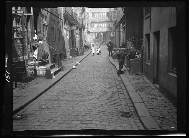 Photo:Europe 1910s Narrow Cobblestone Street Pedestrians Shopfronts