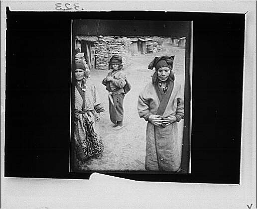 Three Ainu women outside,village lane,structures,buildings,Arnold Genthe,1908
