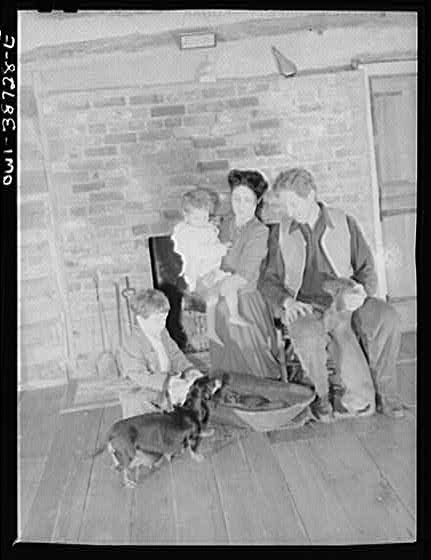 Photo:Family with Child and Dog by Brick Fireplace 1900s Interior Portrait