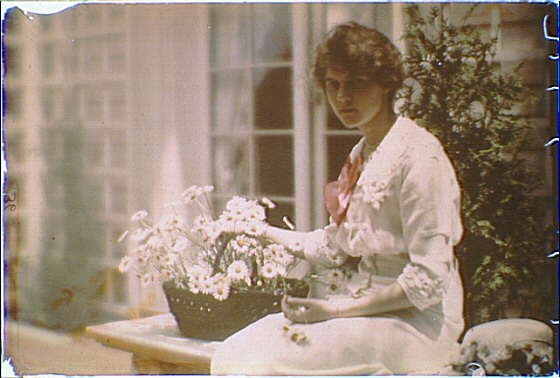 Photo:Woman in White Dress with Basket of Flowers Seated Outdoors 1910s